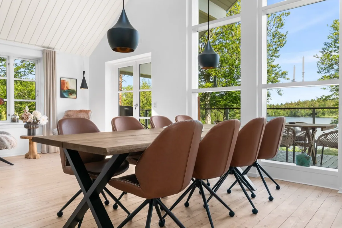 Spisestue med store vinduer og udsigt til sø og skov